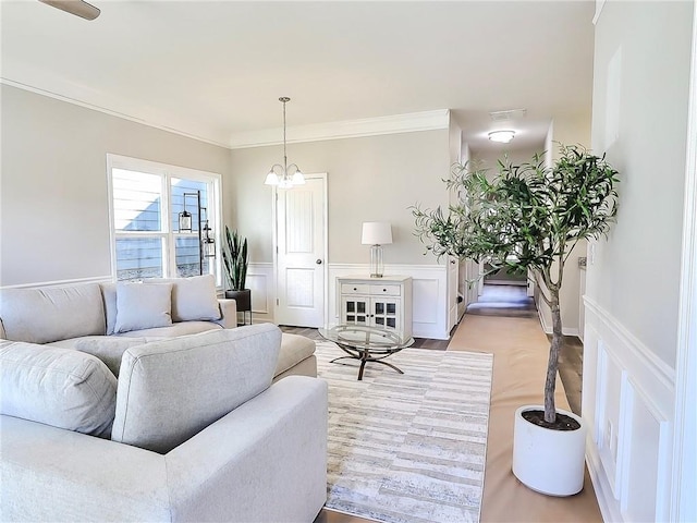 living room featuring light wood-type flooring, an inviting chandelier, and ornamental molding