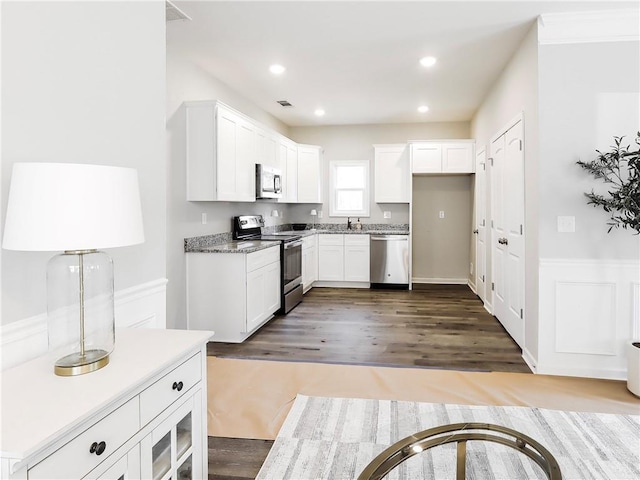 kitchen with white cabinets, sink, crown molding, dark hardwood / wood-style flooring, and stainless steel appliances