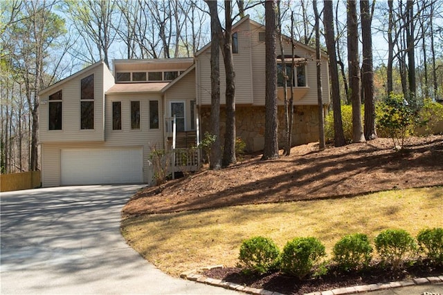 view of front of home with an attached garage, concrete driveway, and stone siding