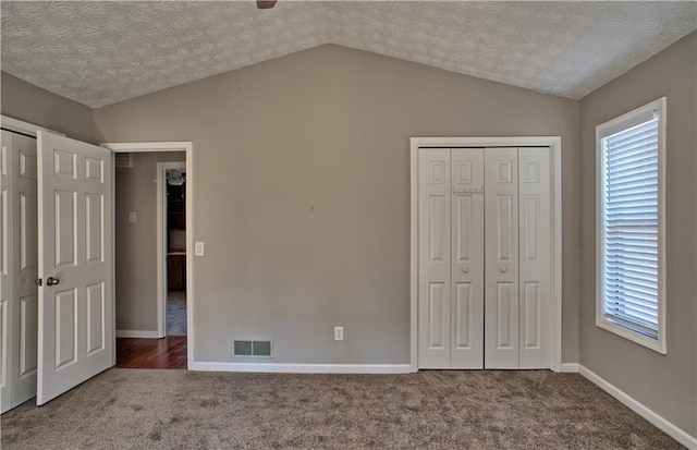 unfurnished bedroom featuring vaulted ceiling, visible vents, multiple windows, and carpet