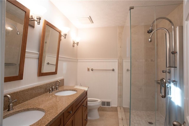 bathroom featuring a sink, a shower stall, toilet, and visible vents