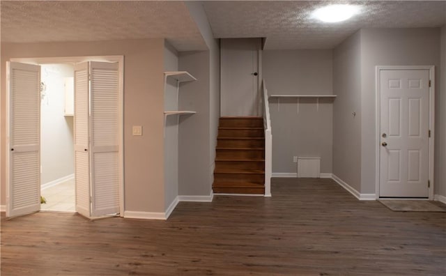 interior space featuring baseboards, a textured ceiling, and wood finished floors