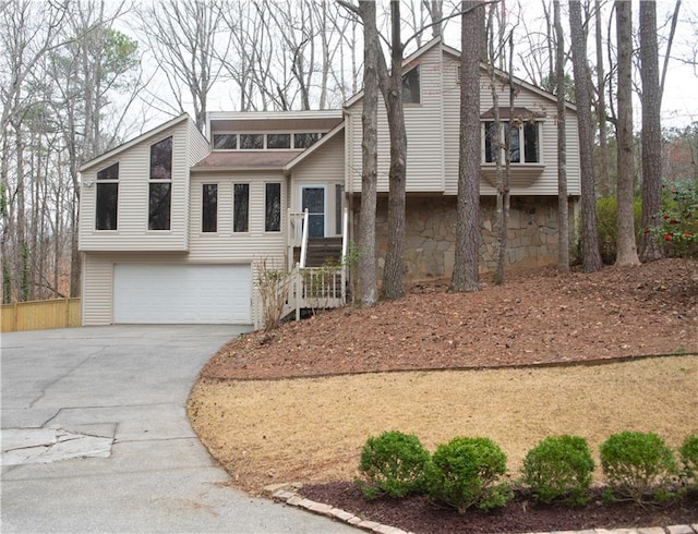 view of front of house featuring an attached garage, concrete driveway, and stone siding