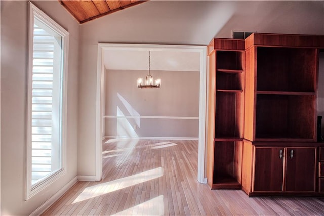 interior space featuring an inviting chandelier, baseboards, vaulted ceiling, and light wood-style flooring