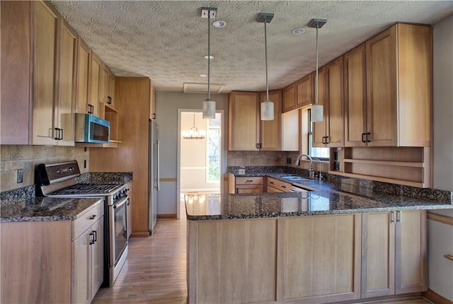 kitchen with backsplash, light wood-type flooring, a sink, a peninsula, and stainless steel appliances