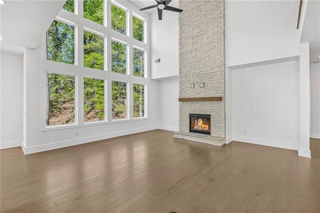 unfurnished living room featuring a fireplace, a high ceiling, a ceiling fan, and baseboards