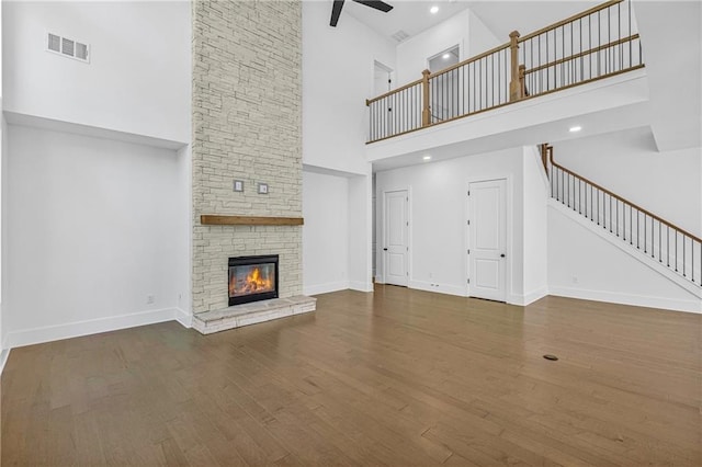 unfurnished living room featuring wood finished floors, visible vents, a high ceiling, and stairs