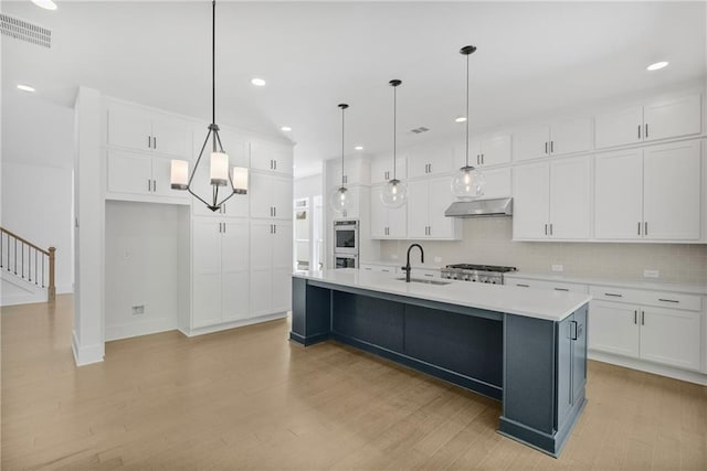 kitchen with white cabinets, stainless steel appliances, a sink, visible vents, and under cabinet range hood