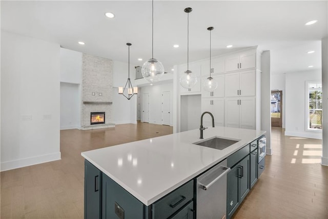 kitchen with white cabinets, light wood-style flooring, a sink, baseboards, and dishwasher