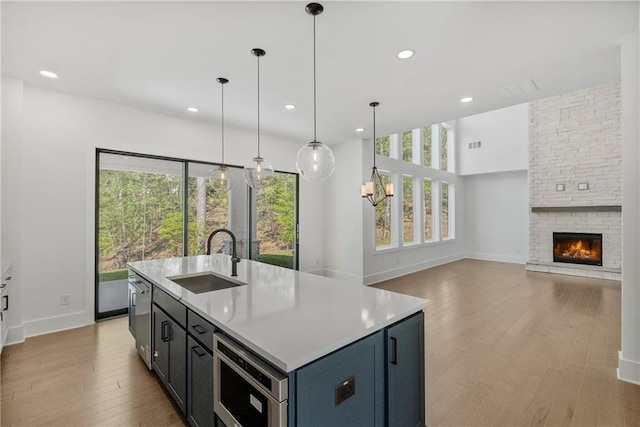 kitchen featuring light wood-style flooring, a sink, baseboards, light countertops, and a fireplace