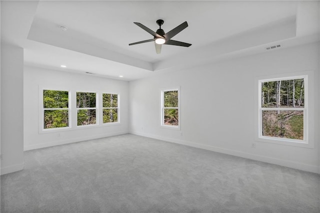 carpeted spare room featuring recessed lighting, a raised ceiling, visible vents, a ceiling fan, and baseboards
