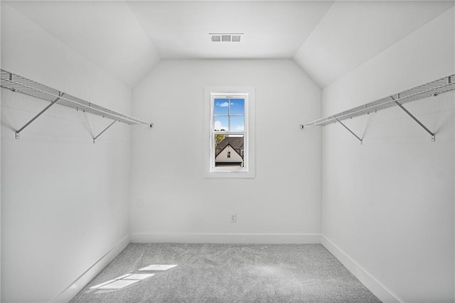 spacious closet with vaulted ceiling, visible vents, and carpet flooring