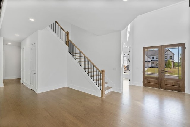foyer featuring baseboards, french doors, wood finished floors, and stairs
