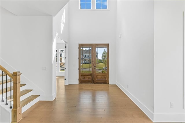 foyer entrance with french doors, a wealth of natural light, stairway, and wood-type flooring