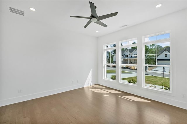 empty room featuring baseboards, visible vents, recessed lighting, a ceiling fan, and wood finished floors