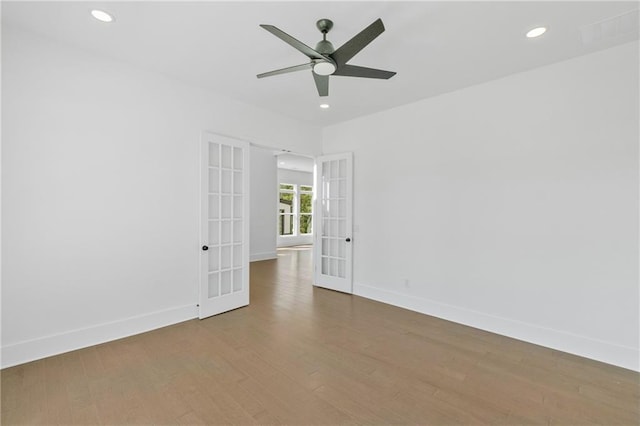 empty room with recessed lighting, wood finished floors, a ceiling fan, and french doors