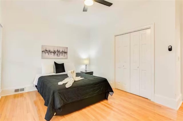 bedroom with ceiling fan, a closet, wood finished floors, and visible vents