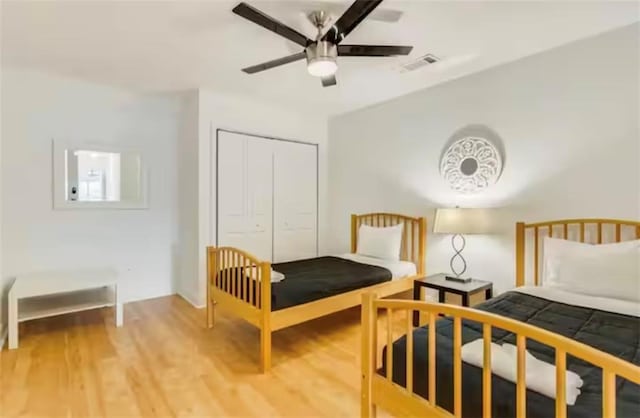 bedroom featuring a ceiling fan, a closet, visible vents, and wood finished floors