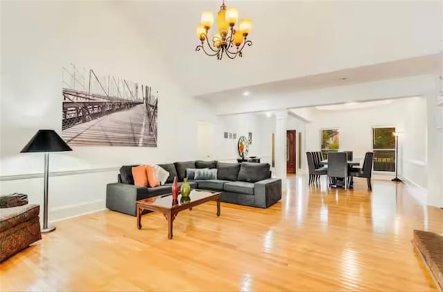 living room with an inviting chandelier, baseboards, wood finished floors, and ornate columns