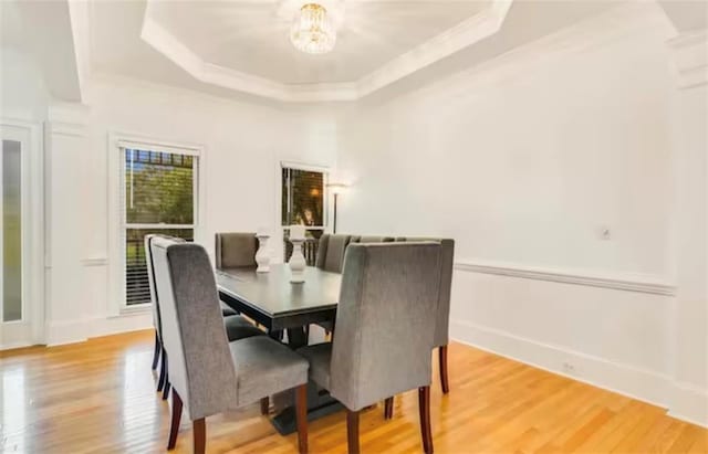 dining room featuring baseboards, a tray ceiling, light wood-type flooring, and a notable chandelier