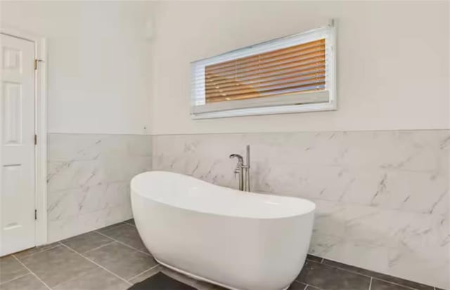 full bathroom with wainscoting, a freestanding bath, and tile patterned floors