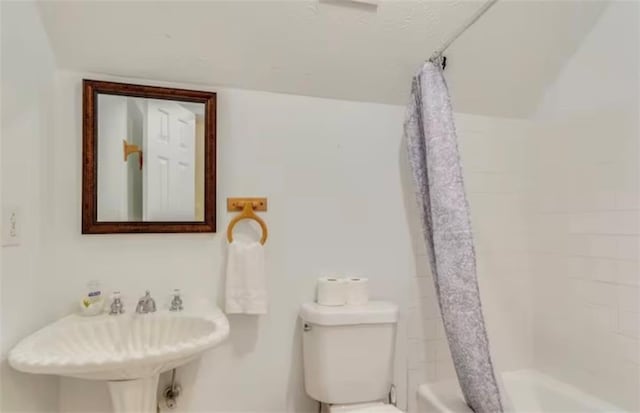 bathroom with curtained shower, a sink, and toilet