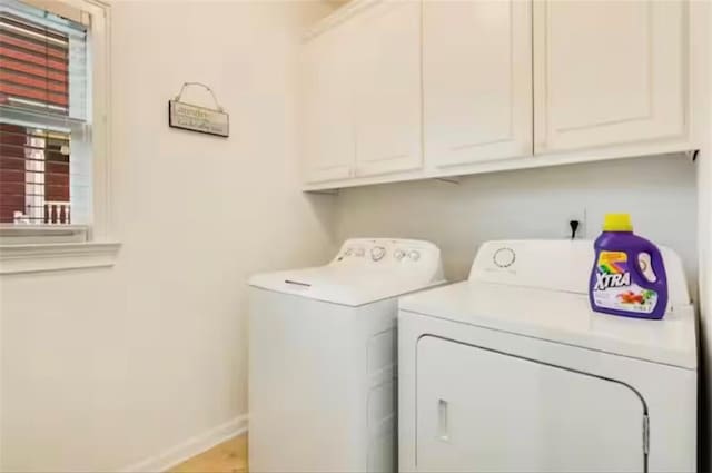 washroom featuring washing machine and dryer, cabinet space, and baseboards