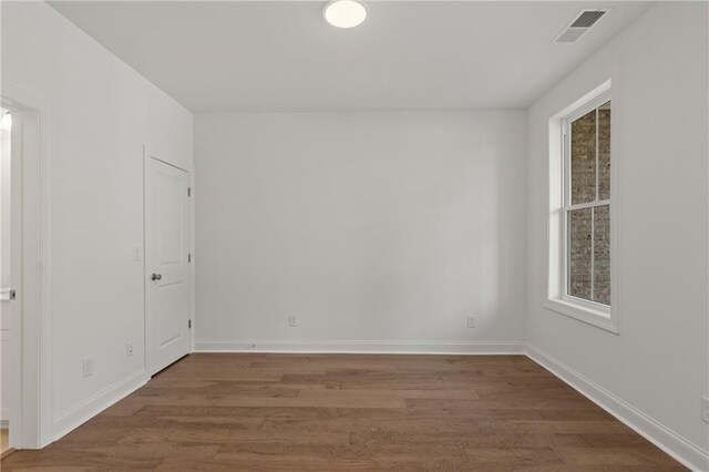 unfurnished room featuring baseboards, wood finished floors, visible vents, and a wealth of natural light