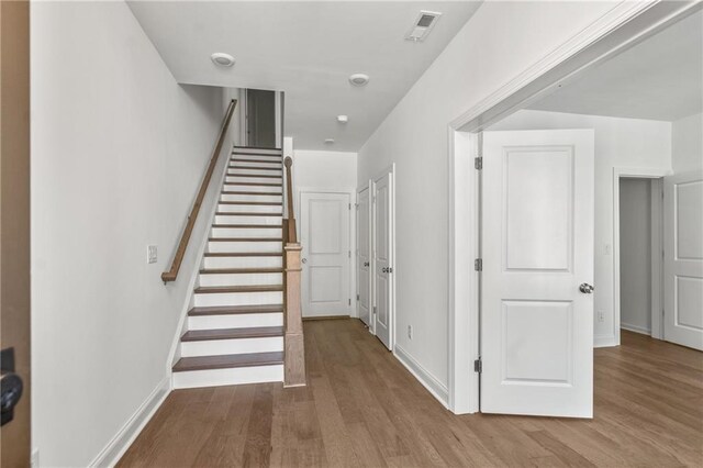 staircase featuring baseboards, wood finished floors, and visible vents