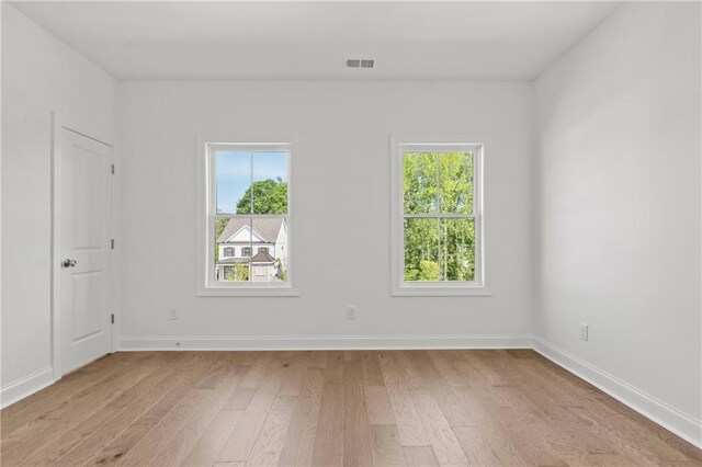 empty room featuring baseboards, visible vents, and light wood-style flooring