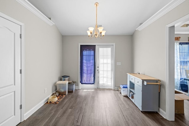 entryway featuring a notable chandelier, dark wood-type flooring, and ornamental molding