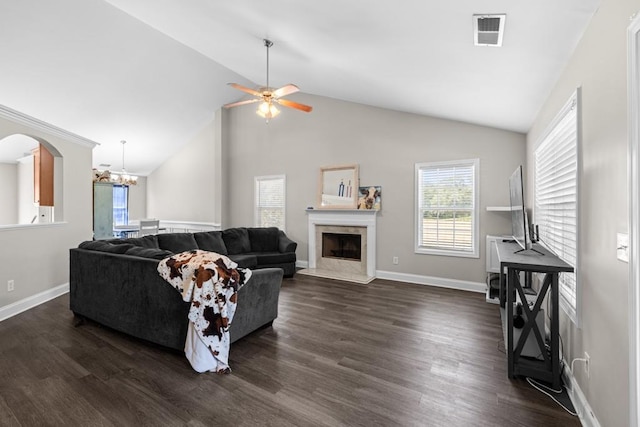 living room featuring ceiling fan with notable chandelier, dark wood-type flooring, a premium fireplace, and vaulted ceiling