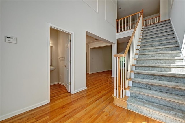 staircase featuring a towering ceiling and hardwood / wood-style floors