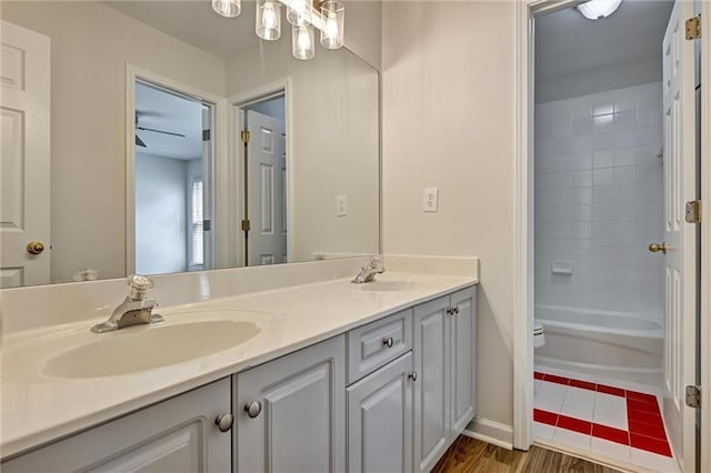 full bathroom featuring tiled shower / bath combo, vanity, a chandelier, and toilet