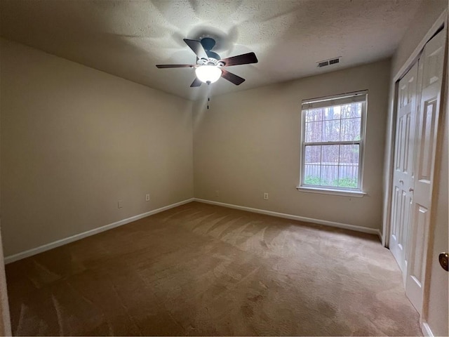 carpeted spare room featuring ceiling fan and a textured ceiling