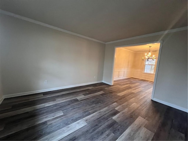 empty room with crown molding, dark hardwood / wood-style flooring, and a notable chandelier