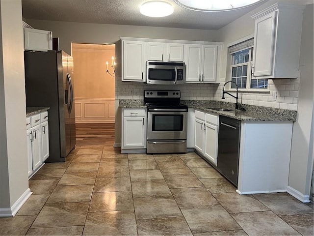 kitchen with sink, white cabinetry, tasteful backsplash, stone counters, and stainless steel appliances