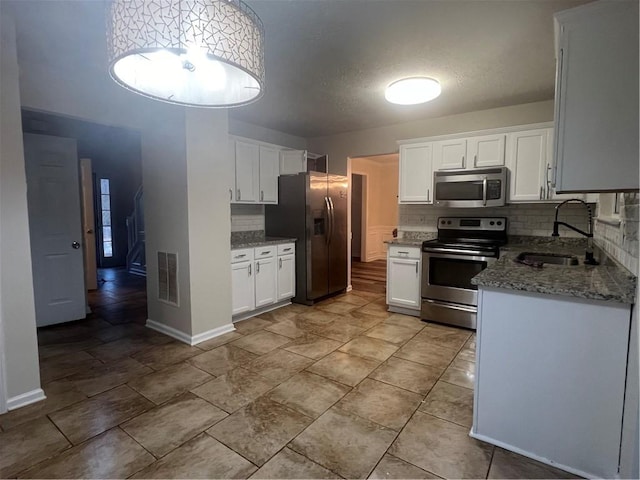 kitchen featuring sink, stone counters, white cabinetry, stainless steel appliances, and tasteful backsplash