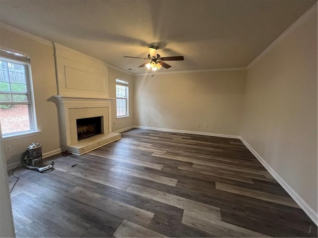 unfurnished living room with crown molding, a large fireplace, ceiling fan, and dark hardwood / wood-style flooring