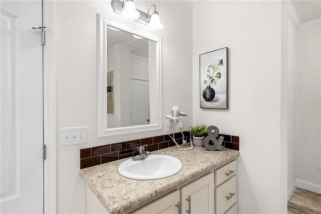 bathroom with vanity, decorative backsplash, baseboards, and ornamental molding