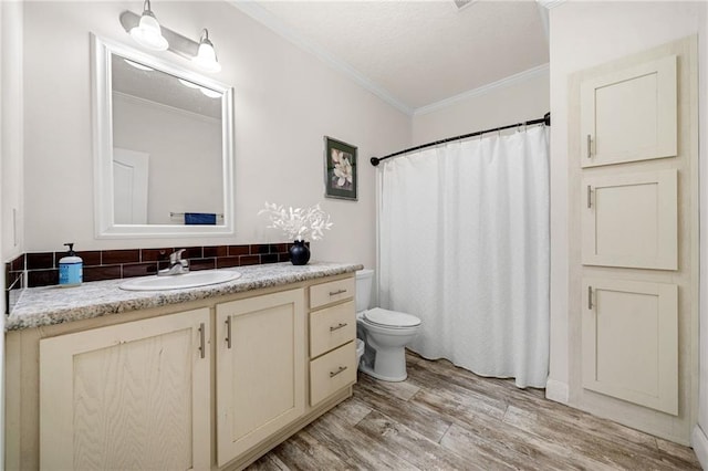 full bathroom with curtained shower, toilet, ornamental molding, wood finished floors, and vanity