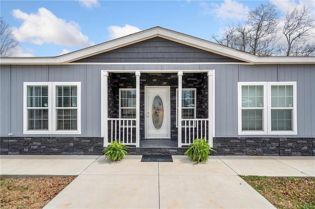 property entrance with stone siding and a porch