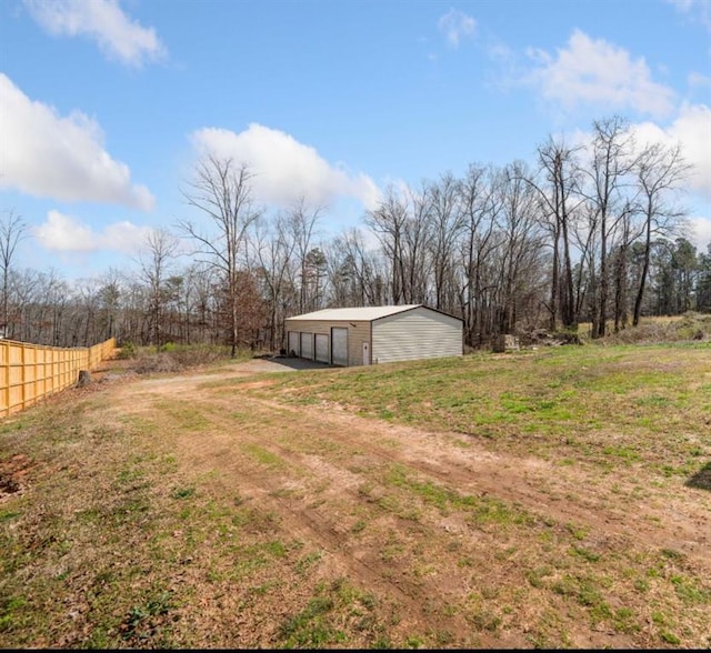 view of yard featuring an outbuilding, a detached garage, fence, and an outdoor structure