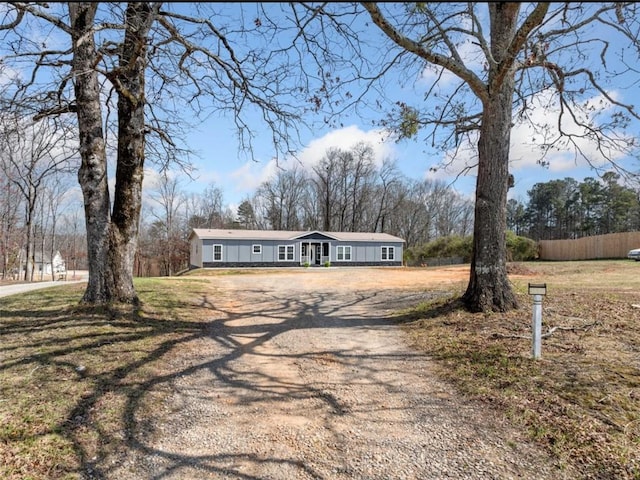 manufactured / mobile home with a front lawn, fence, and dirt driveway