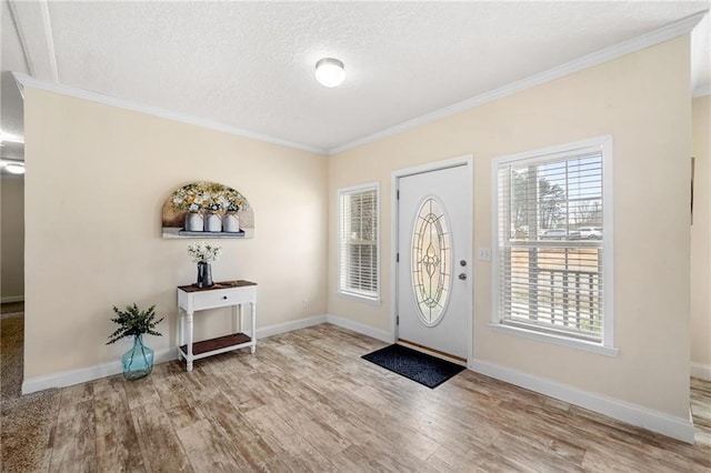 foyer entrance featuring baseboards, a textured ceiling, wood finished floors, and crown molding