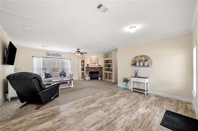 living room with visible vents, ornamental molding, wood finished floors, baseboards, and ceiling fan