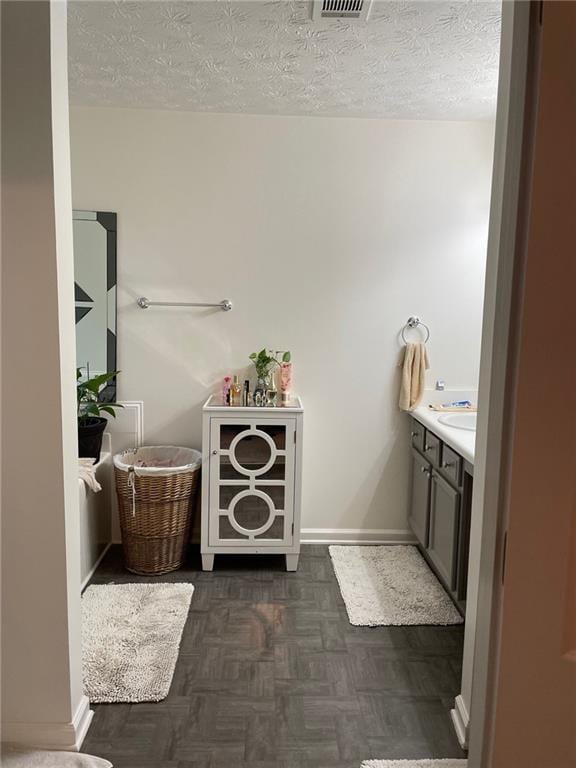 bathroom with a textured ceiling, vanity, and parquet flooring