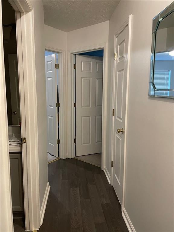 hallway featuring a textured ceiling and dark hardwood / wood-style floors