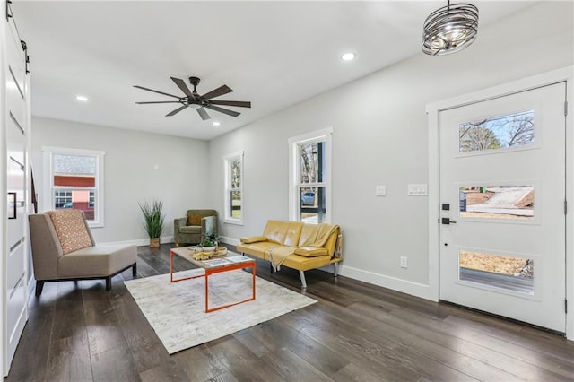 living room with ceiling fan, dark hardwood / wood-style flooring, and a barn door