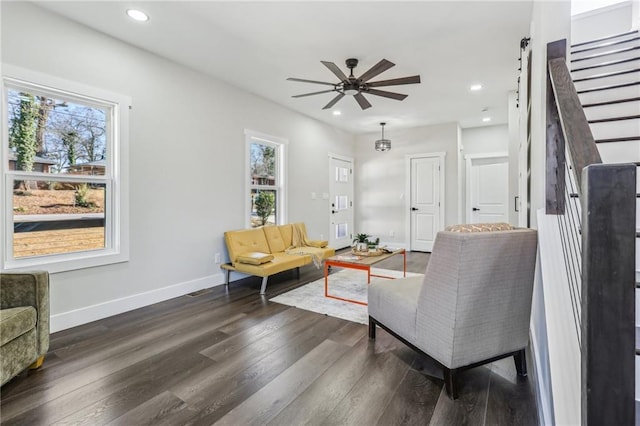 living room featuring ceiling fan, dark hardwood / wood-style flooring, and a barn door